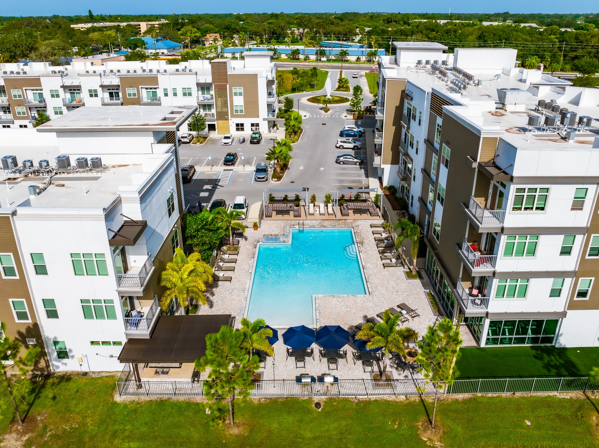 A swimming pool surrounded by apartment buildings and palm trees.